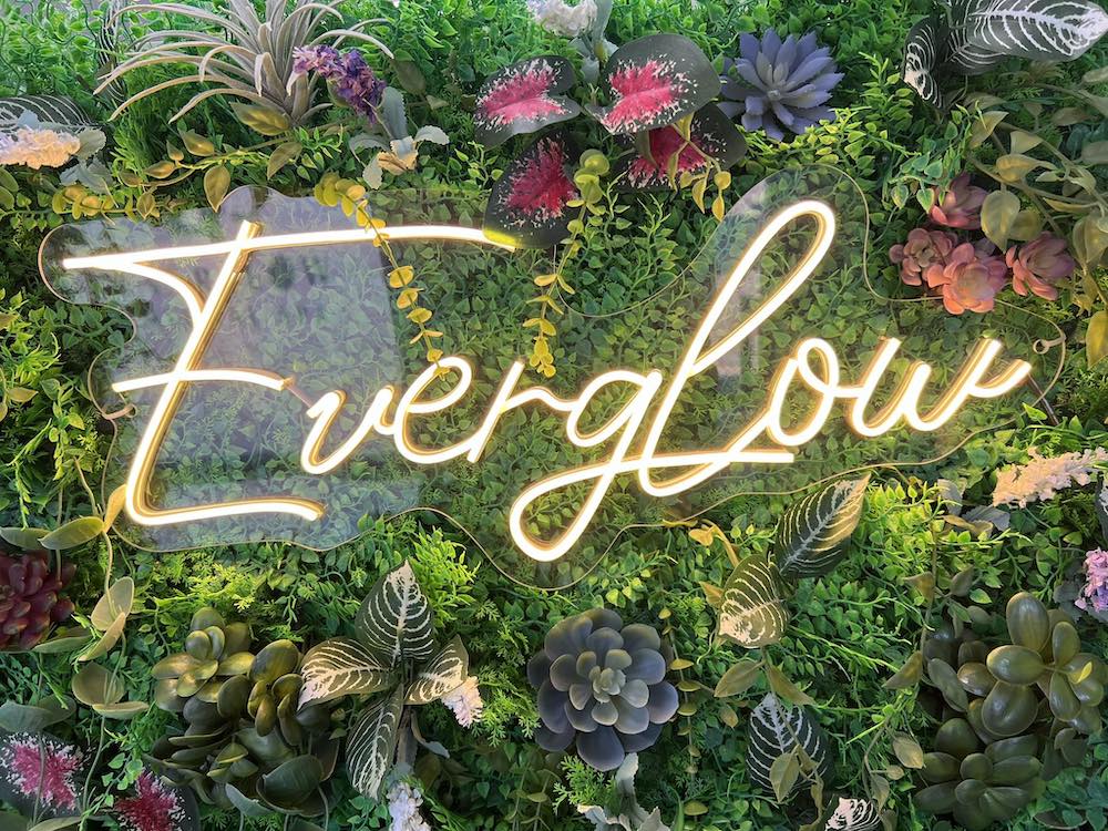 The word "Everglow" in lights among plants and flowers