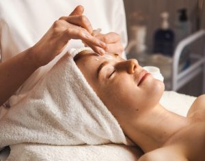 woman smiling and relaxing while having a facial treatment